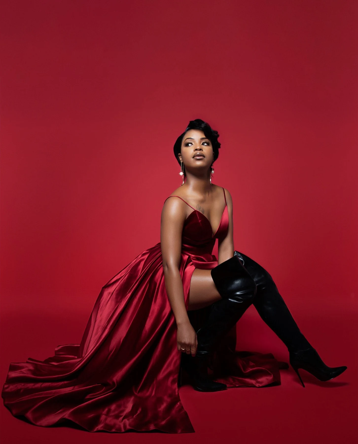 Featured portrait retouching of a woman in a red satin gown against a red studio backdrop