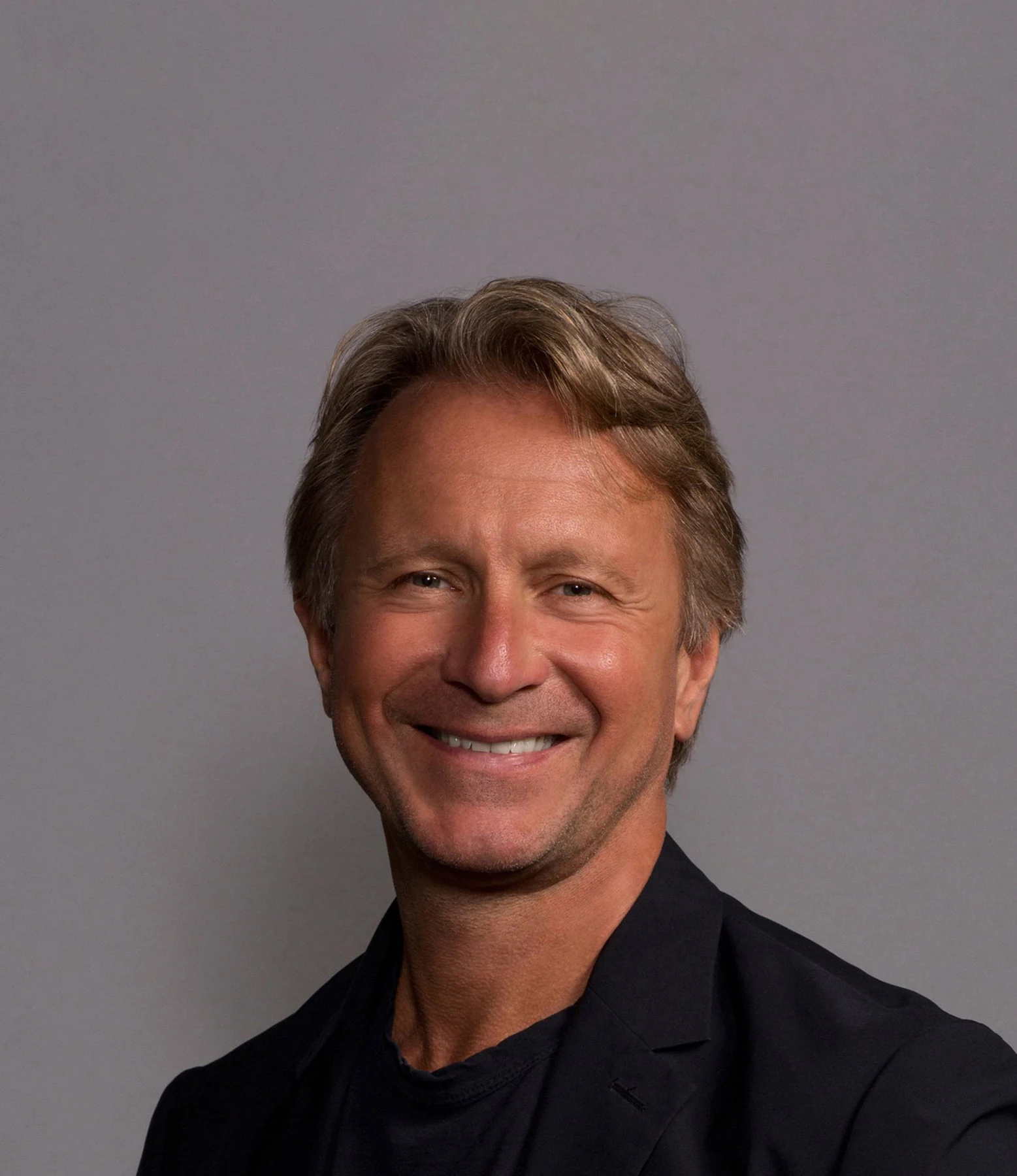 Featured headshot retouching of a smiling man in a dark jacket
