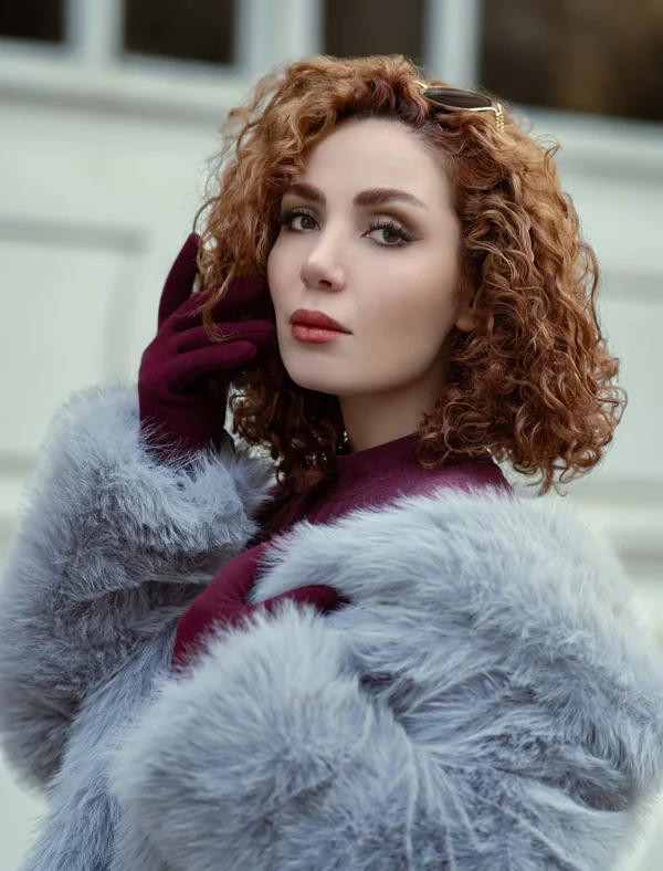 Studio portrait of a woman with curly auburn hair after skin and tonal retouching
